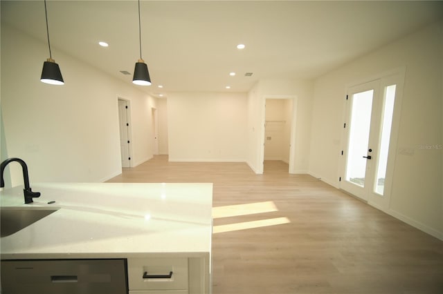 kitchen with french doors, sink, decorative light fixtures, light hardwood / wood-style flooring, and stainless steel dishwasher