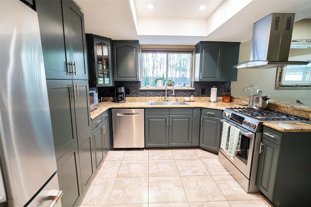 kitchen with a tray ceiling, backsplash, appliances with stainless steel finishes, a sink, and extractor fan