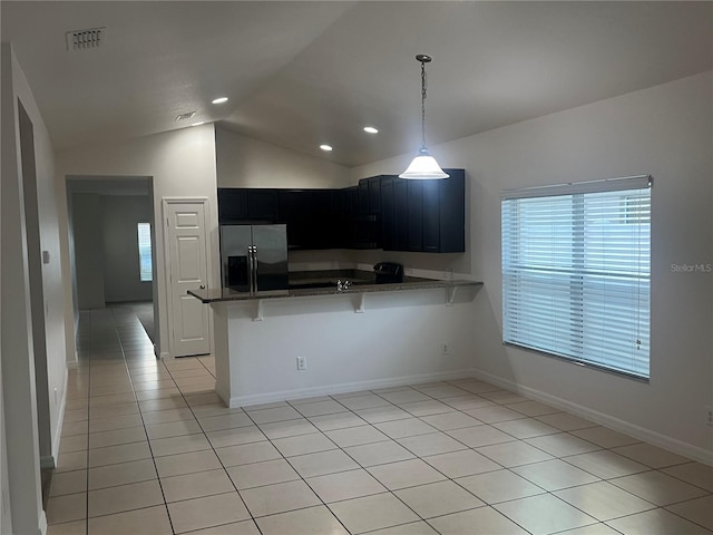 kitchen with a breakfast bar area, vaulted ceiling, stainless steel fridge, kitchen peninsula, and pendant lighting