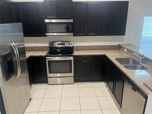 kitchen with light stone counters, sink, light tile patterned floors, and stainless steel appliances