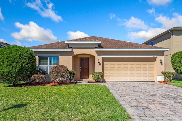 ranch-style home with stucco siding, decorative driveway, roof with shingles, an attached garage, and a front yard