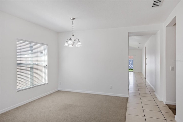 empty room featuring light tile patterned floors, visible vents, a notable chandelier, and light colored carpet