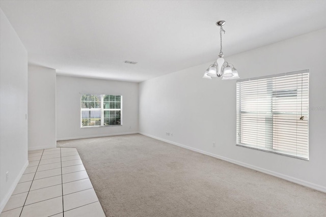 unfurnished room featuring a notable chandelier, visible vents, baseboards, and light carpet