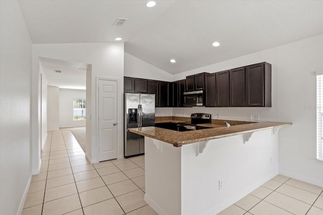 kitchen featuring a breakfast bar area, lofted ceiling, a peninsula, light tile patterned flooring, and appliances with stainless steel finishes