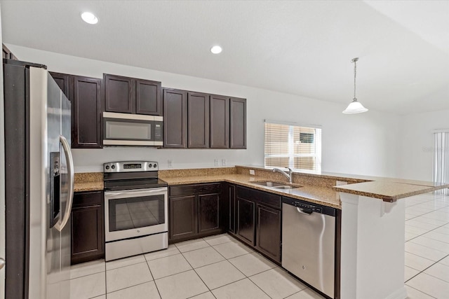 kitchen featuring light tile patterned floors, a peninsula, a sink, dark brown cabinetry, and appliances with stainless steel finishes