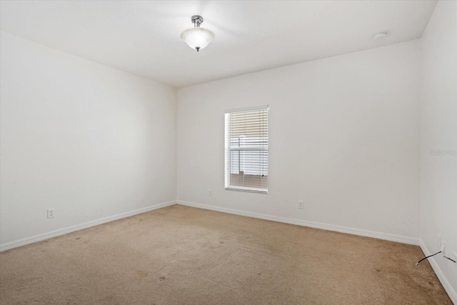 spare room with baseboards and light carpet