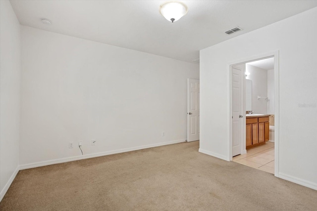 unfurnished bedroom with visible vents, light carpet, a sink, connected bathroom, and baseboards