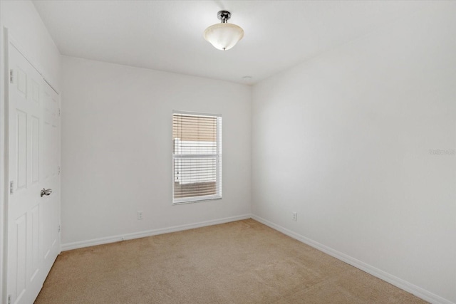 spare room with baseboards and light carpet