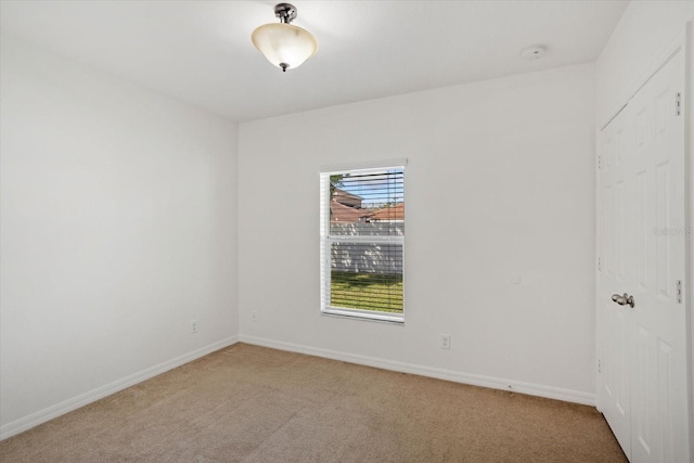 spare room with baseboards and light carpet