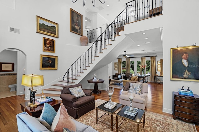 living room with a high ceiling, wood-type flooring, and ceiling fan