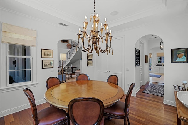 dining area featuring crown molding, an inviting chandelier, dark hardwood / wood-style flooring, and a tray ceiling