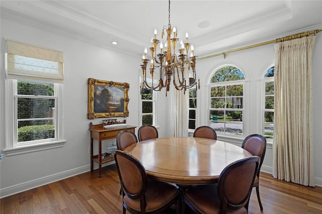 dining room with an inviting chandelier, a tray ceiling, crown molding, and dark hardwood / wood-style floors