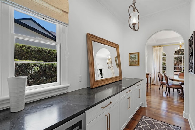 bar featuring white cabinetry, decorative light fixtures, dark wood-type flooring, and crown molding