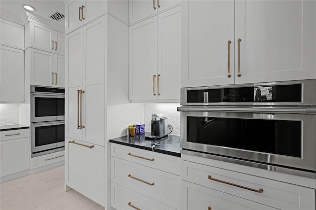 kitchen with white cabinetry, stainless steel double oven, and tasteful backsplash