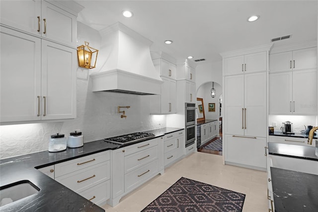 kitchen featuring premium range hood, decorative light fixtures, tasteful backsplash, white cabinetry, and stainless steel appliances