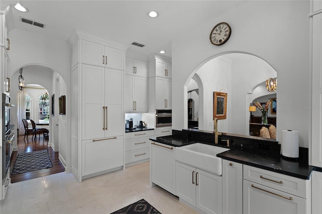 kitchen featuring white cabinetry, oven, and sink