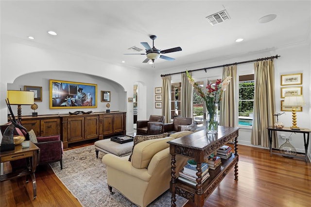 living room with wood-type flooring, ornamental molding, and ceiling fan