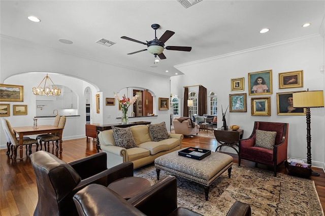 living room featuring ornamental molding, wood-type flooring, and ceiling fan with notable chandelier