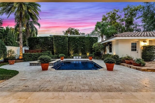 pool at dusk featuring a patio area