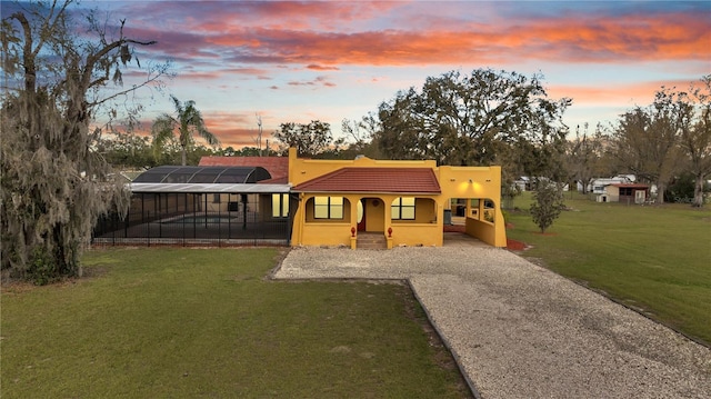 view of front of house featuring gravel driveway, stucco siding, a tile roof, and a yard