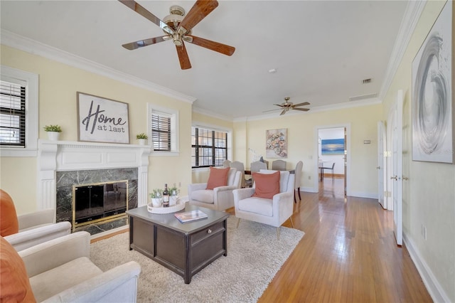 living room with a fireplace, crown molding, baseboards, and wood finished floors