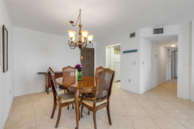 tiled dining space with an inviting chandelier and a textured ceiling