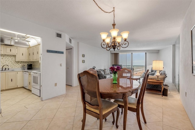 dining area with ceiling fan with notable chandelier, sink, a textured ceiling, and light tile patterned floors