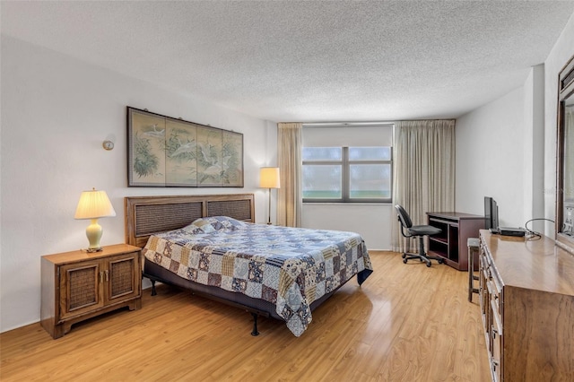 bedroom with a textured ceiling and light wood-type flooring