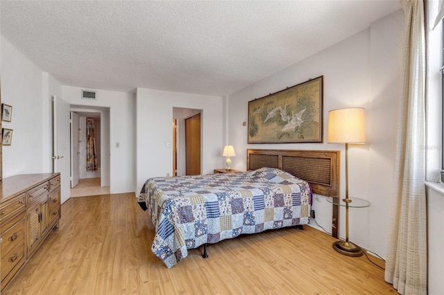 bedroom with a textured ceiling and light wood-type flooring