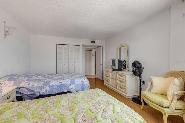 bedroom with light hardwood / wood-style floors, a closet, and a textured ceiling