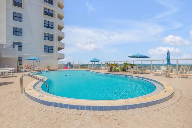 view of pool featuring a patio and a water view