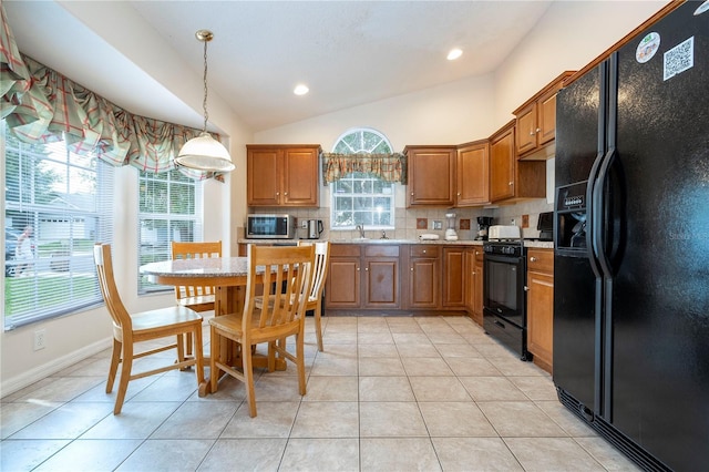 kitchen featuring vaulted ceiling, light tile patterned flooring, tasteful backsplash, light stone counters, and black appliances