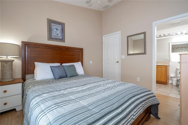 bedroom with light wood-type flooring and ensuite bath