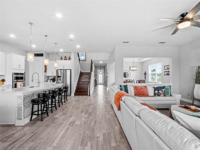 living area with light wood-type flooring, visible vents, recessed lighting, and stairs