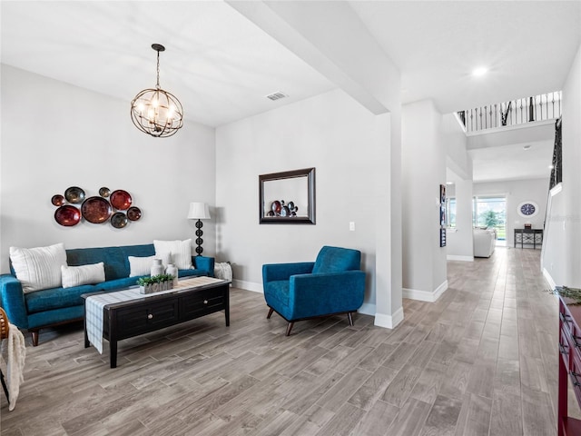 living room featuring light wood-style floors, baseboards, visible vents, and a chandelier