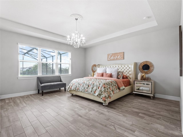 bedroom featuring wood finished floors, a raised ceiling, and baseboards