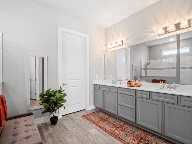 bathroom with double vanity, a walk in shower, a sink, and wood finished floors