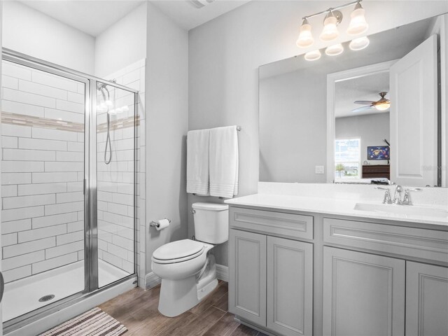 bathroom featuring a ceiling fan, wood finished floors, toilet, and a shower stall