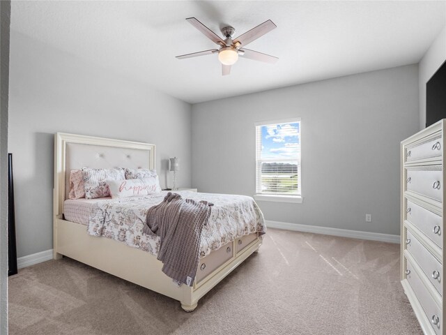 bedroom with light colored carpet, ceiling fan, and baseboards