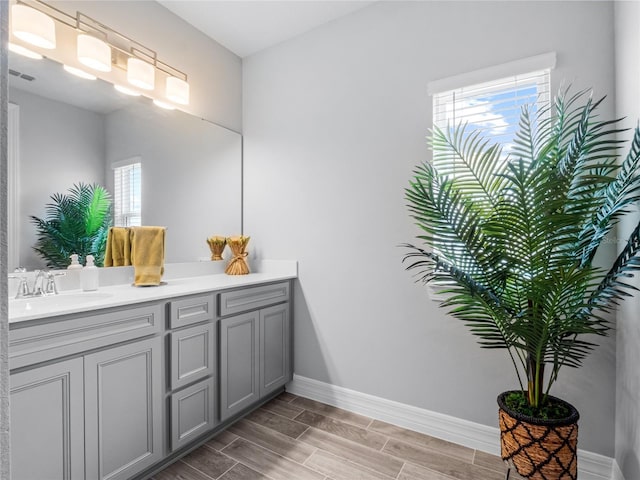 bathroom featuring wood tiled floor, visible vents, baseboards, and vanity