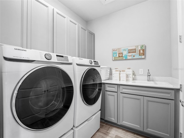 laundry room featuring cabinet space, washer and dryer, a sink, and wood finish floors