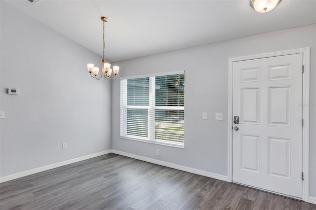 unfurnished dining area featuring baseboards, a chandelier, and wood finished floors