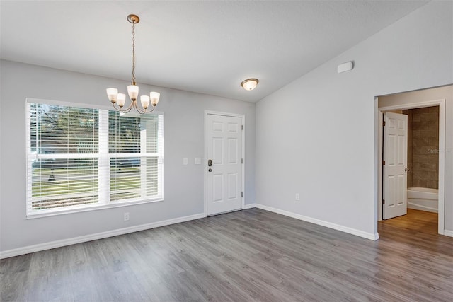 unfurnished dining area featuring a chandelier, vaulted ceiling, baseboards, and wood finished floors