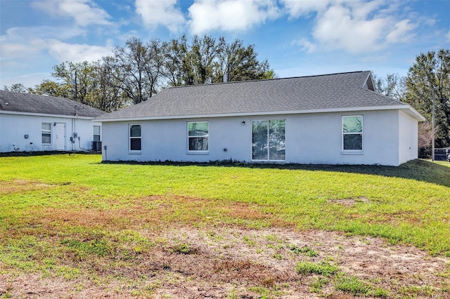 back of property with roof with shingles, a lawn, and stucco siding