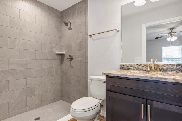 full bath with toilet, ceiling fan, a tile shower, and vanity