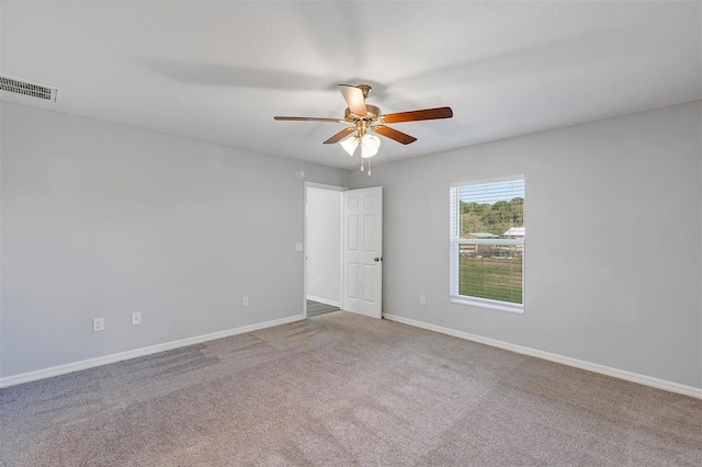 empty room featuring carpet floors, visible vents, baseboards, and a ceiling fan