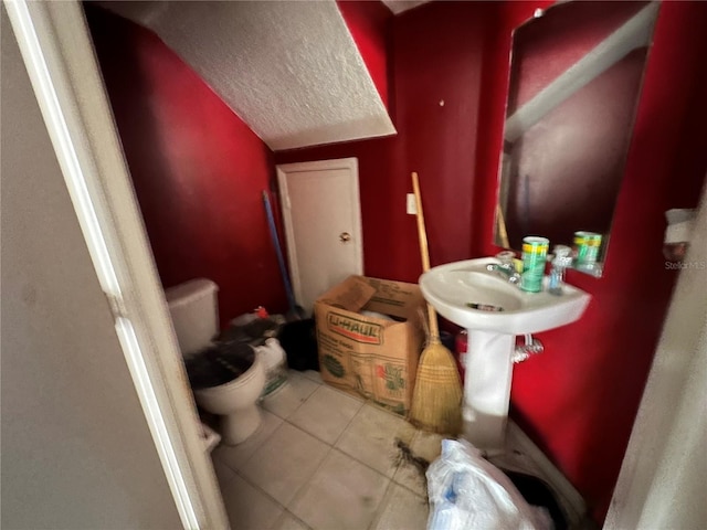 bathroom with tile patterned flooring, lofted ceiling, a textured ceiling, and toilet