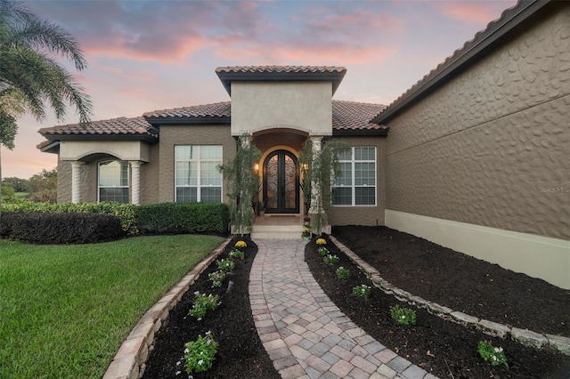 exterior entry at dusk with french doors and a yard