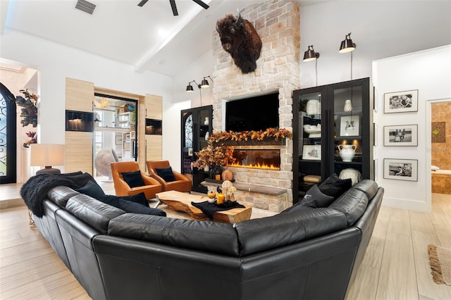 living room with a fireplace, high vaulted ceiling, beamed ceiling, and light wood-type flooring