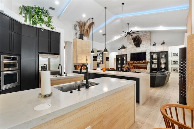 kitchen with appliances with stainless steel finishes, decorative light fixtures, sink, a large fireplace, and ceiling fan